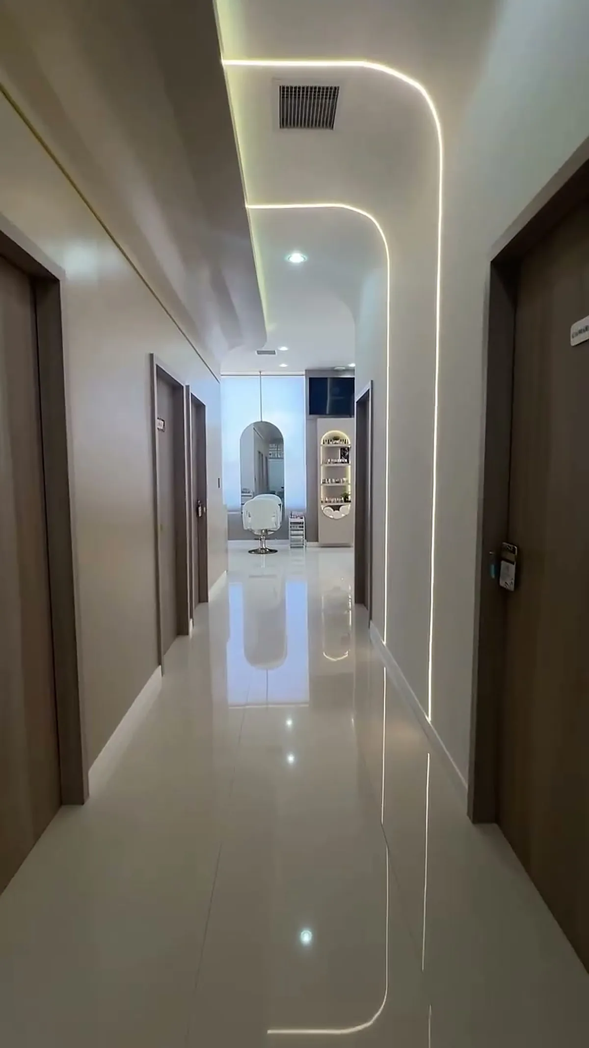 Pasillo hacia las cabinas privadas, con puertas de madera y luz lineal